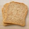 Two whole wheat bread slices on a light wood surface, airy interior, browned crust.