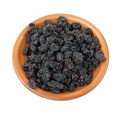 Wooden bowl filled with dried black raisins.