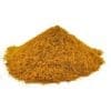 Pile of yellow-brown granulated powder on a white background, resembling a common seasoning.